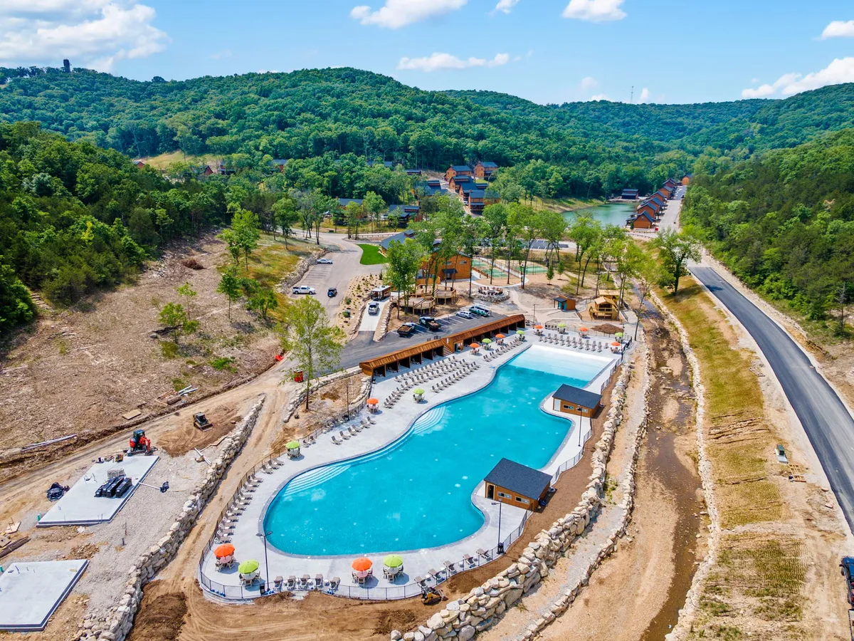 An inviting exterior with a large swimming pool, colorful lounge chairs, a wooden amenities structure, and surrounding greenery. The scene is lively, capturing the spirit of community events, swimming, and relaxation under the sun.