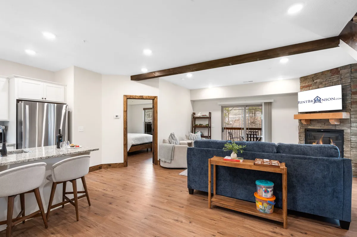 A spacious, open-concept living area with a central kitchen island, modern fireplace, comfortable seating, and decor that exudes warmth. The kitchen flows seamlessly into the living space, creating a perfect environment for entertaining, family gatherings, or relaxing by the fire.